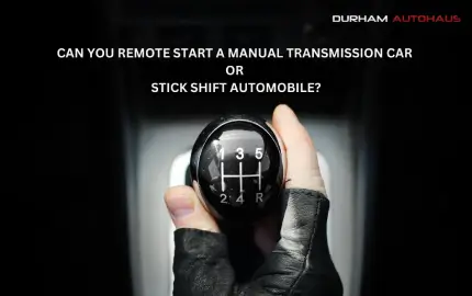 A close-up of a gloved hand gripping a manual transmission gear shift, with the text above reading, "CAN YOU REMOTE START A MANUAL TRANSMISSION CAR OR STICK SHIFT AUTOMOBILE?" The image has a dark background with a spotlight effect on the gear shift.